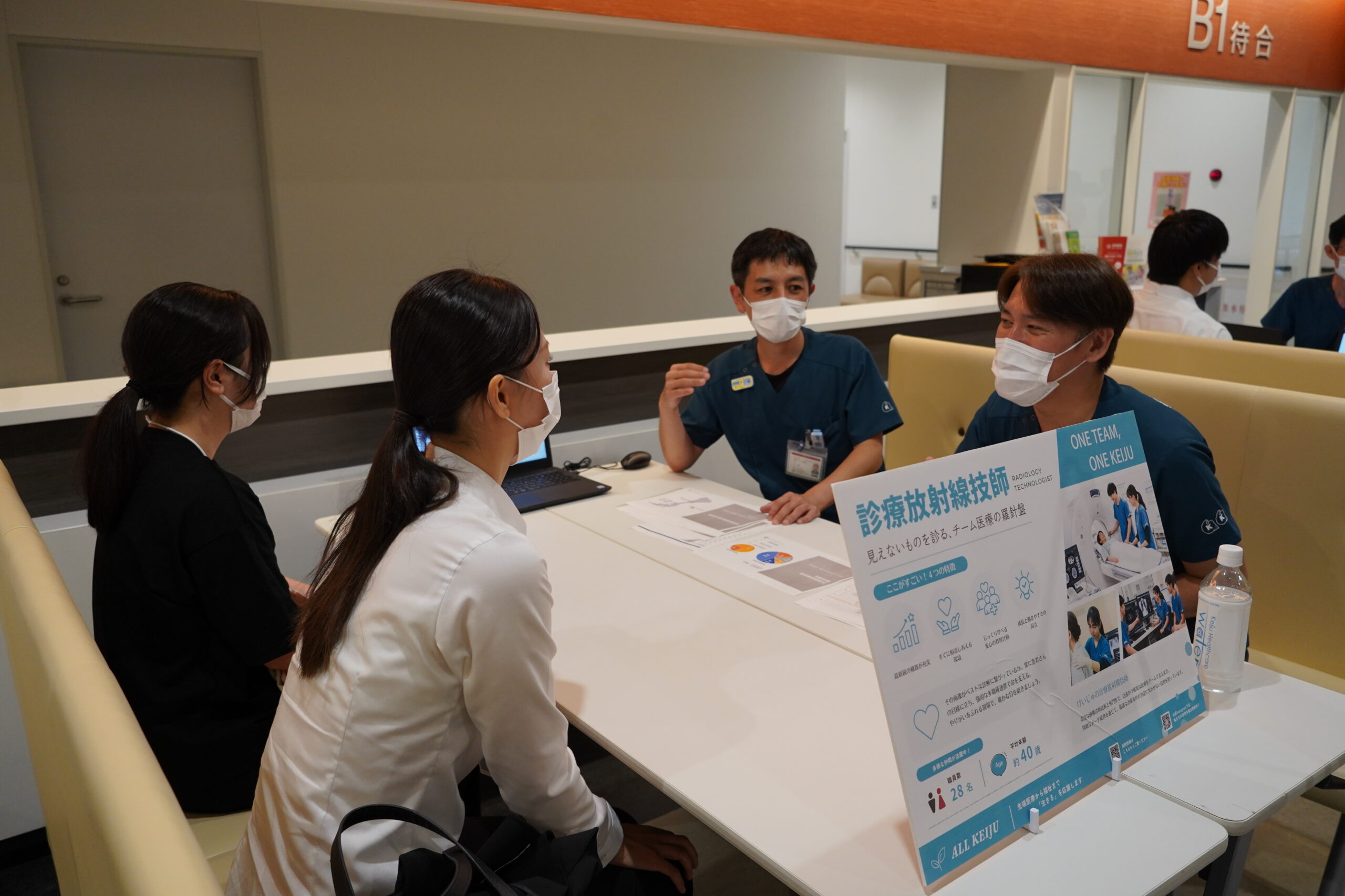 診療放射線技師ブースで、テーブルを囲んで職員と参加者が話している様子