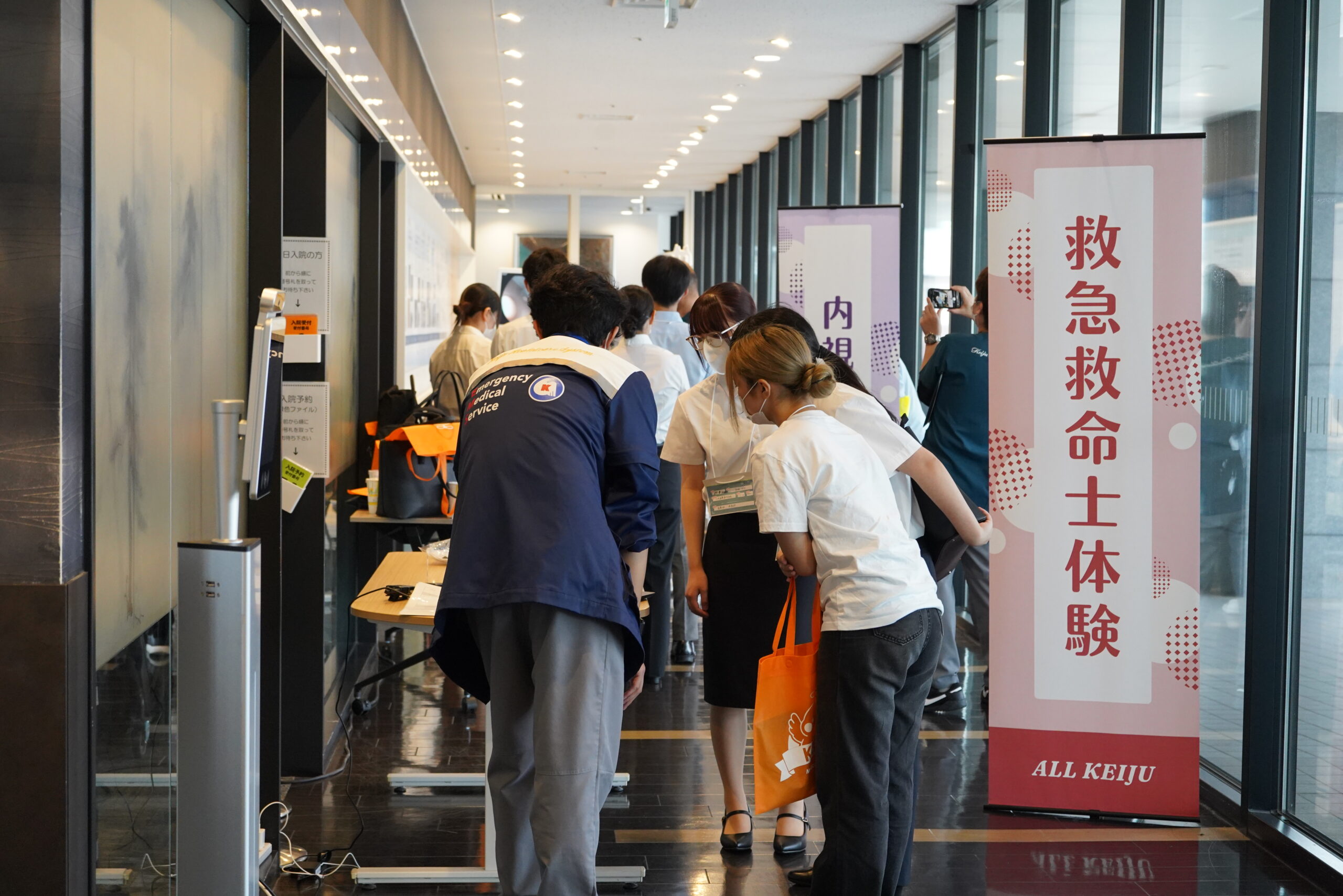 海が見える廊下に設けられた救急救命士体験ブース。のぼりの前に参加者が集まっている様子