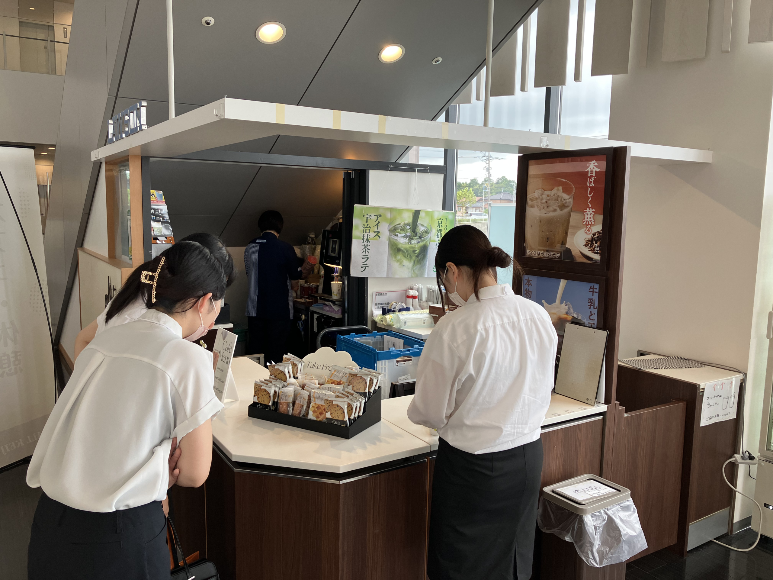 院内のローソン machi café のカウンターで、飲み物やお菓子を選んでいる参加者