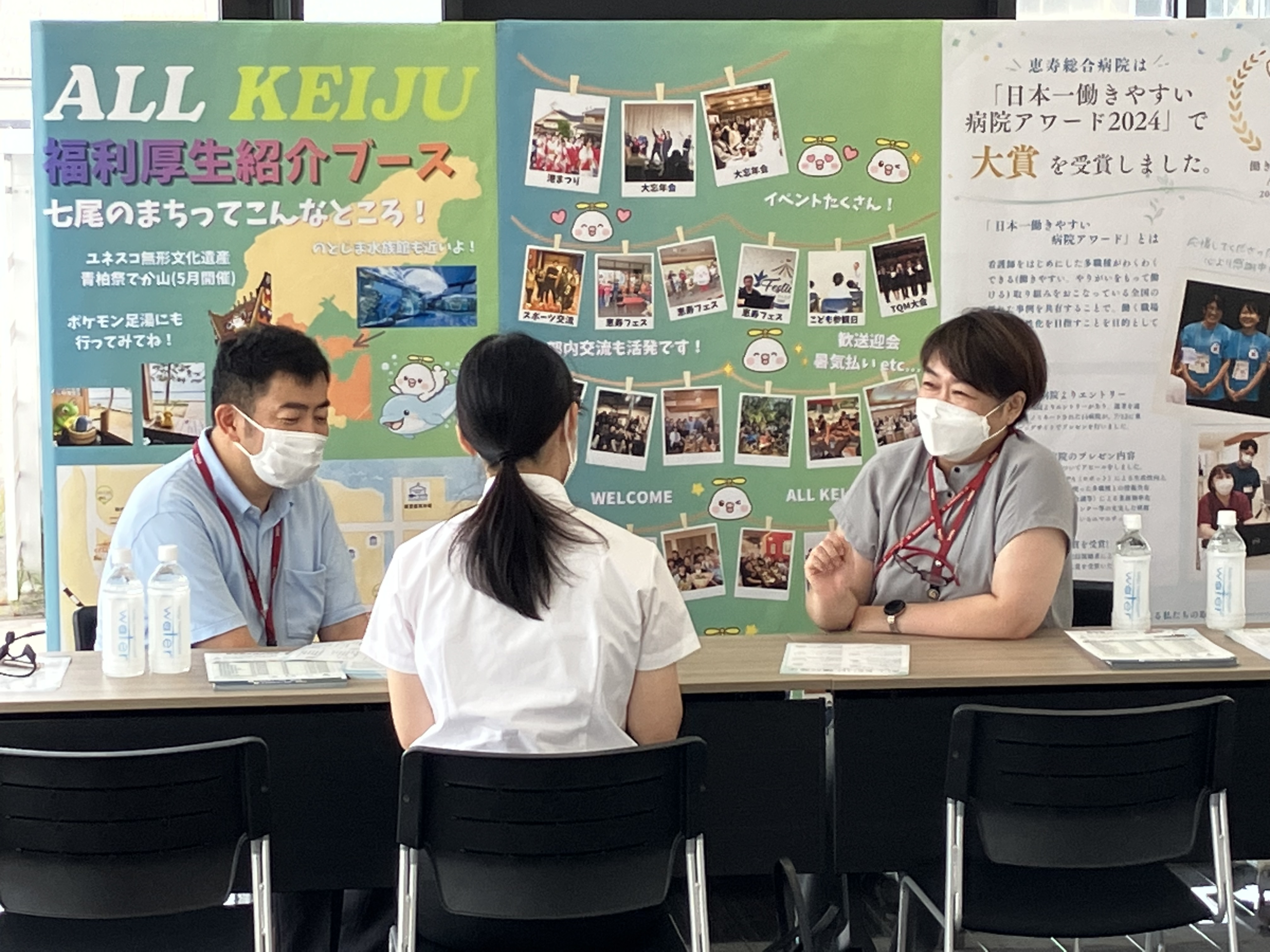 福利厚生紹介ブースで、掲示パネルを背に担当者2名が参加者へ制度を説明している様子